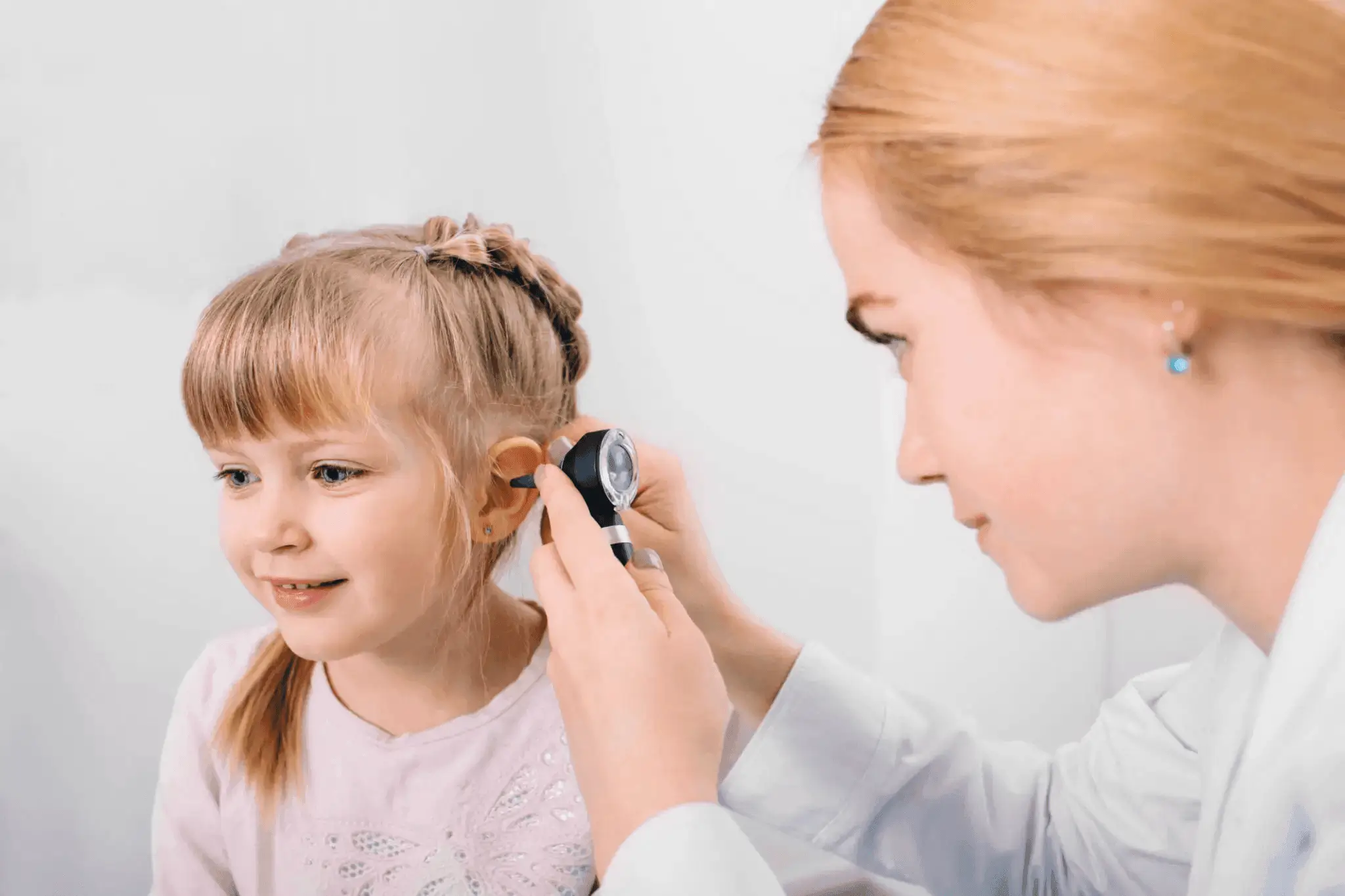 Doctor examining girl's ear with otoscope.
